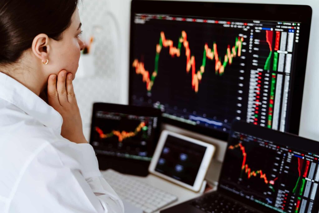 Época dos dividendos está à porta. Como encaixar dinheiro extra com ações? jovem mulher, especialista em mercados, analisa no ecran do seu computador os gráficos de ações de empresas que pagam dividendos