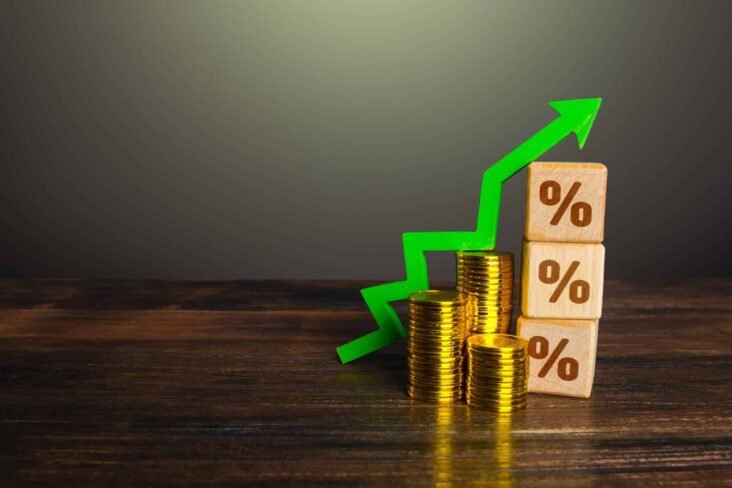 Seta ascendente sobre pilha de moedas a simbolizar aumento dos juros