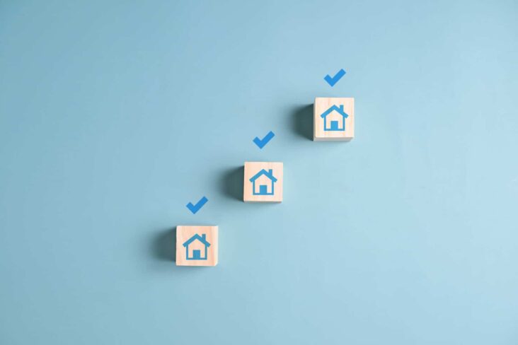 Três cubos brancos dispostos em cima de uma mesa, na diagonal, com o desenho de uma casa estampados