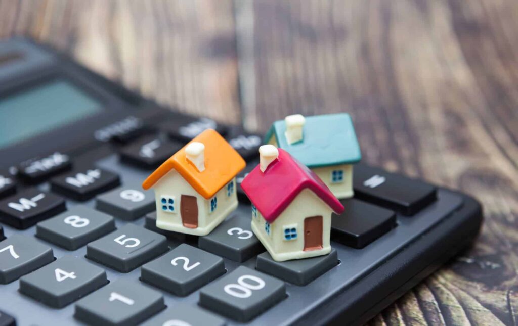 calculadora com casas em miniatura em cima a ilustrar as despesas do condomínio