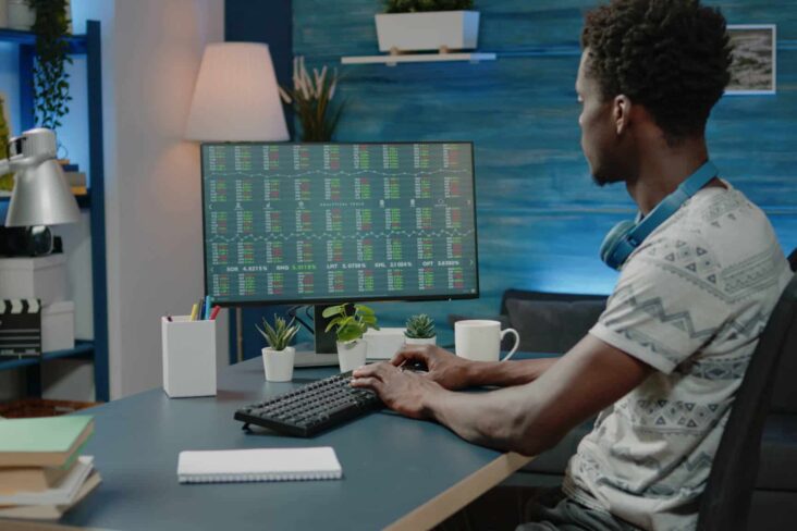 Investidor está sentado em frente ao computador, onde analisar a evolução do mercado bolsista mundial em 2024