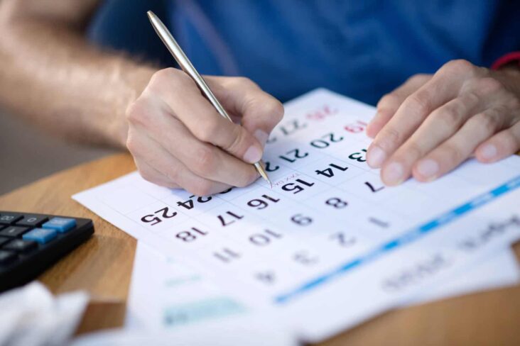 homem a anotar no calendário em papel as datas mais relevantes da agenda fiscal 2025