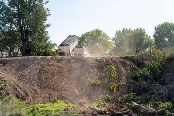 Camião despeja terra num terreno, onde está a realizar-se uma obra de construção