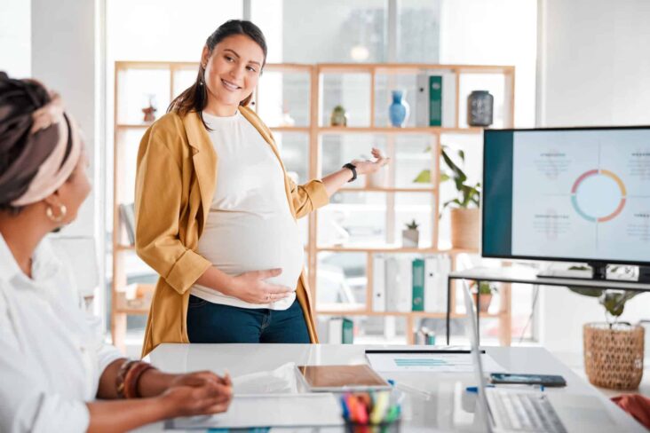 Trabalhadora grávida, faz uma apresentação de um projeto a uma colega de trabalho