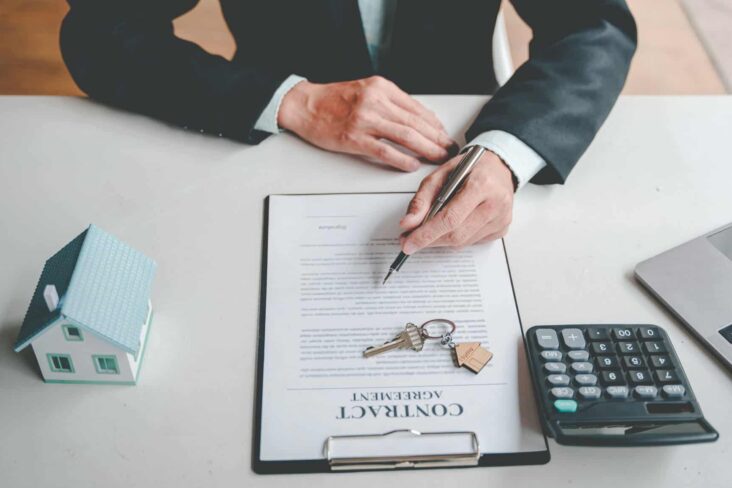 Inquilino revê um contrato de arrendamento. Em cima do contrato estão uma chaves de casa