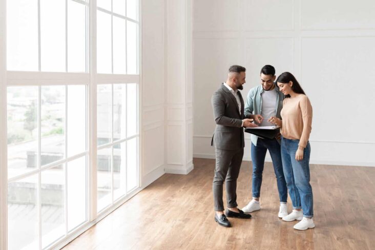 Casal de jovens visita uma casa para comprar acompanhado pelo agente imobiilário