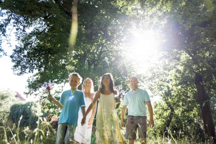 Família composta por um casal de pais e um casal de filhos, passeia na floresta