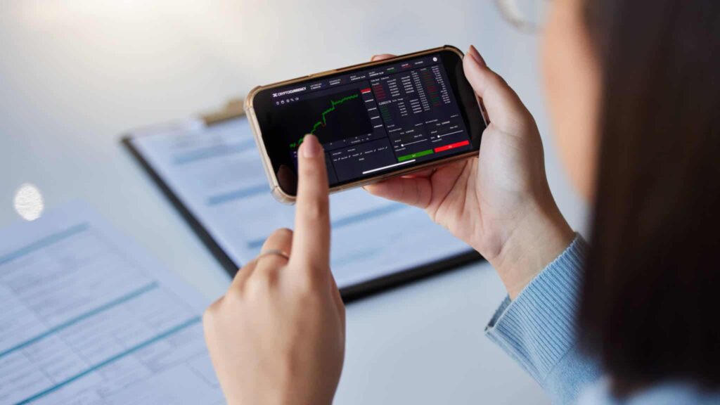 telefone nas mãos de uma mulher com uma app de negociação de instrumentos financeiros.