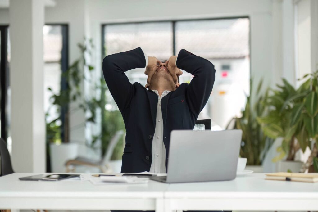 homem em frente ao computador com as mãos na cabeça após atrasar na entrega da declaração de IRS e ter uma perda de benefícios fiscais no IRS