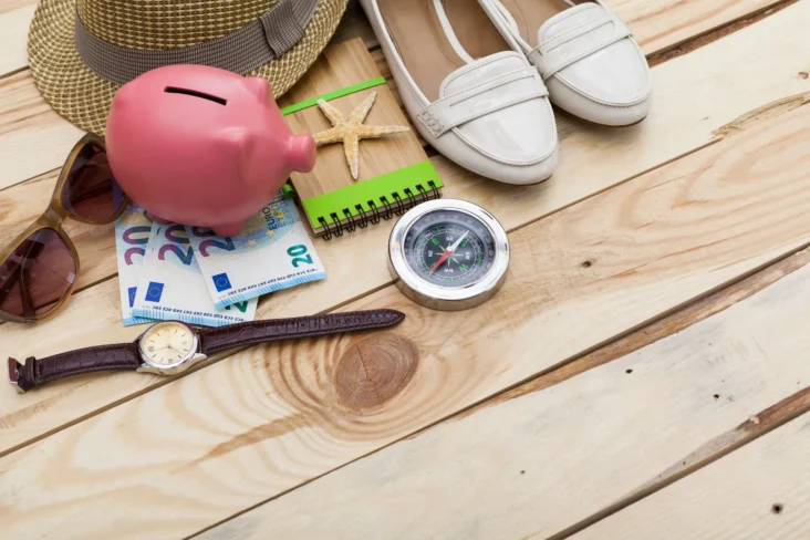 acessórios de férias e porquinho mealheiro para ilustrar poupar nas férias