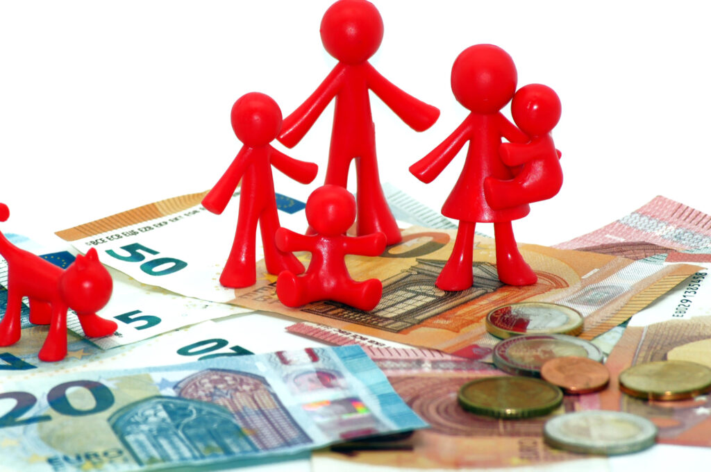 imagem de bonecos vermelhos a simbolizar uma família sobre notas e moedas de euro - para ilustrar artigo sobre "Um terço das famílias não fala de dinheiro com filhos até 6 anos"