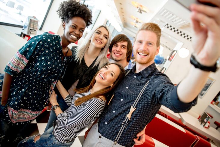 Grupo de jovens, na casa dos 20 anos, pousam para fotografia.