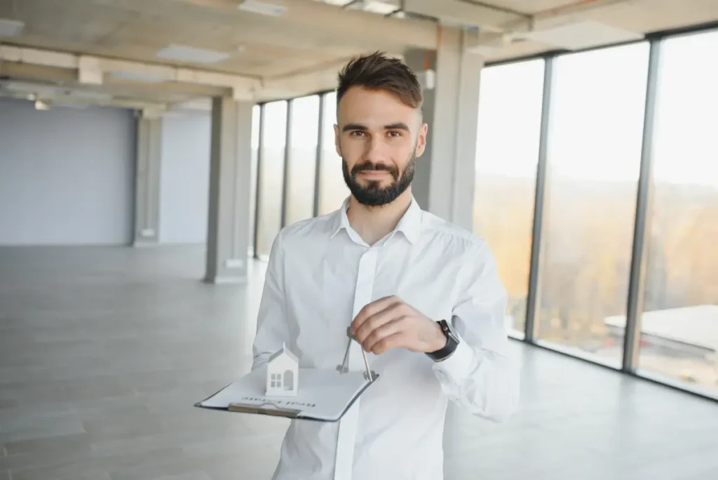 Jovem de camisa com um contrato na mão e uma chave de casa na outra a ilustrar que recorreu ao crédito habitação com garantia do Estado
