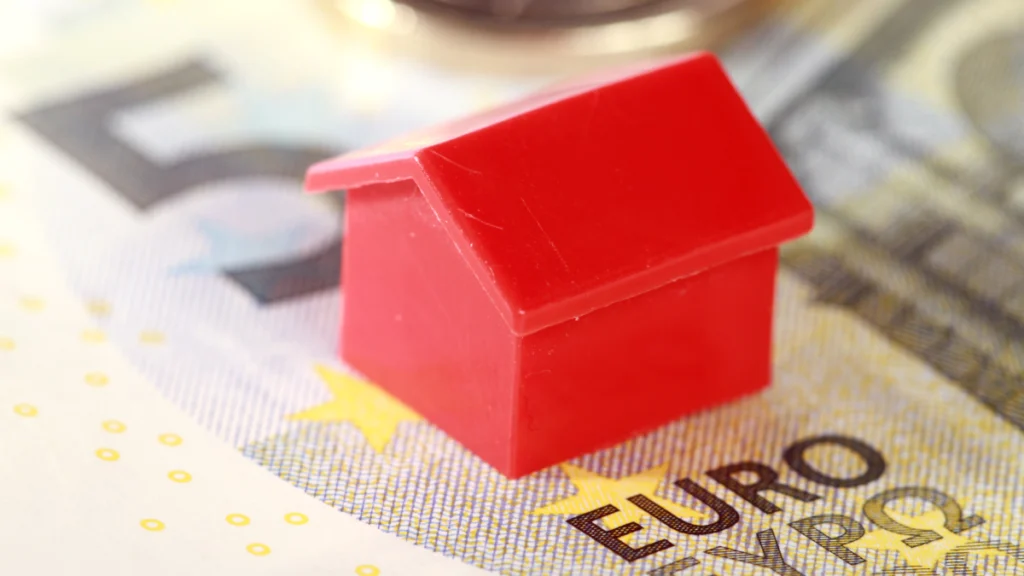 Modelo miniatura de uma habitação em cima de uma nota de cinco euros