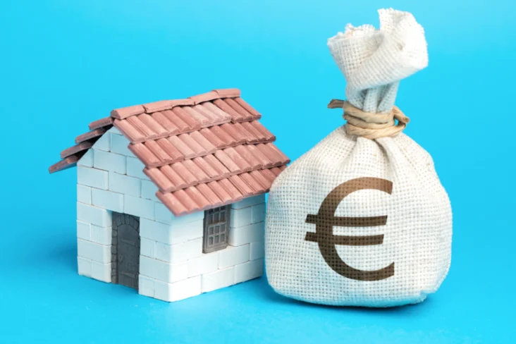 Casa de brincar com saco de dinheiro num fundo azul