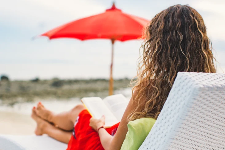 Mulher relaxa a ler um livro na praia