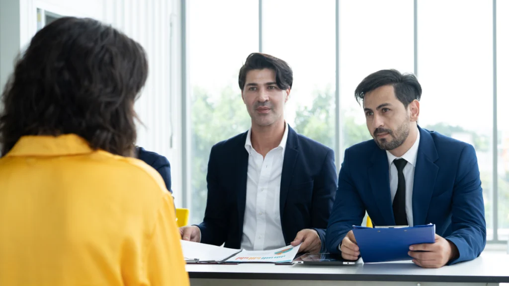 Dois entrevistadores falam com mulher em entrevista de emprego