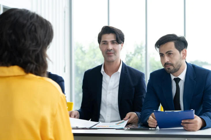 Dois entrevistadores falam com mulher em entrevista de emprego