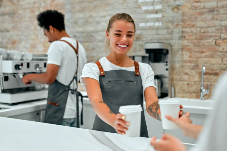 Jovens trabalham num bar a servir cafés