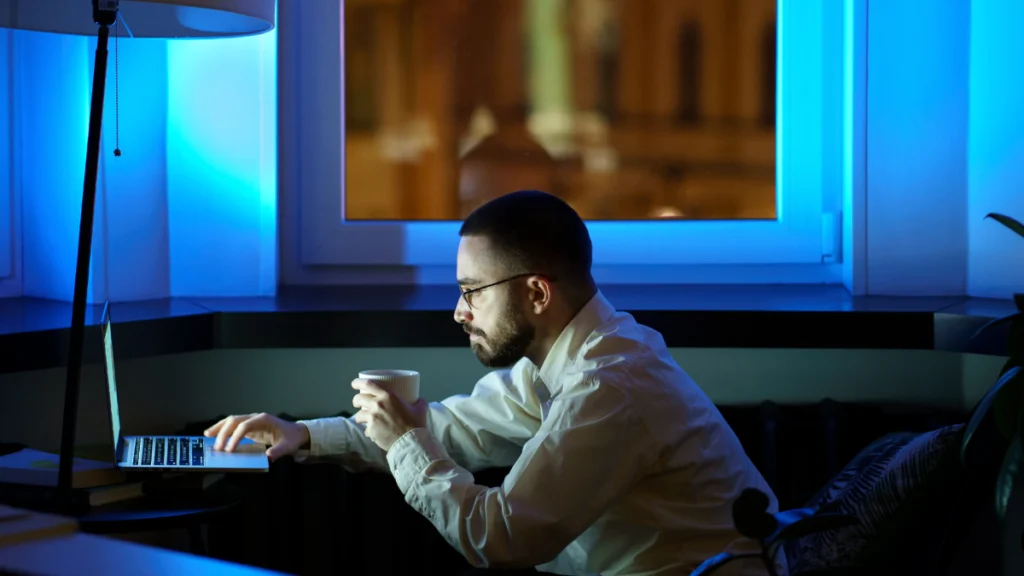 Homem a trabalhar com computador durante a noite, visivelmente exausto