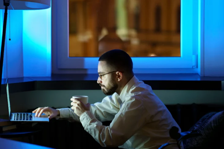 Homem a trabalhar com computador durante a noite, visivelmente exausto